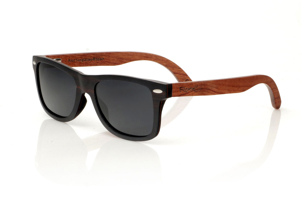 Wood eyewear of Ebony modelo OSCAR. Gafas de sol de madera OSCAR, destaca su estilo inspirado en los clásicos, ofreciendo una silueta ancha que capta la atención. Estas gafas están meticulosamente fabricadas en capas de madera laminada, combinando ébano en el exterior y caoba en el centro, creando un efecto visual único y elegante, realzado por remaches plateados en el frontal. Las varillas de caoba prometen no solo estilo, sino también una durabilidad excepcional. Además de su diseño impecable, las OSCAR garantizan una visión clara y una protección total, asegurando que tus ojos estén protegidos con el máximo confort. Medidas: 149x45 mm. Calibre: 54. Con las OSCAR, experimentarás la perfecta unión entre moda y funcionalidad. | Root Sunglasses® 